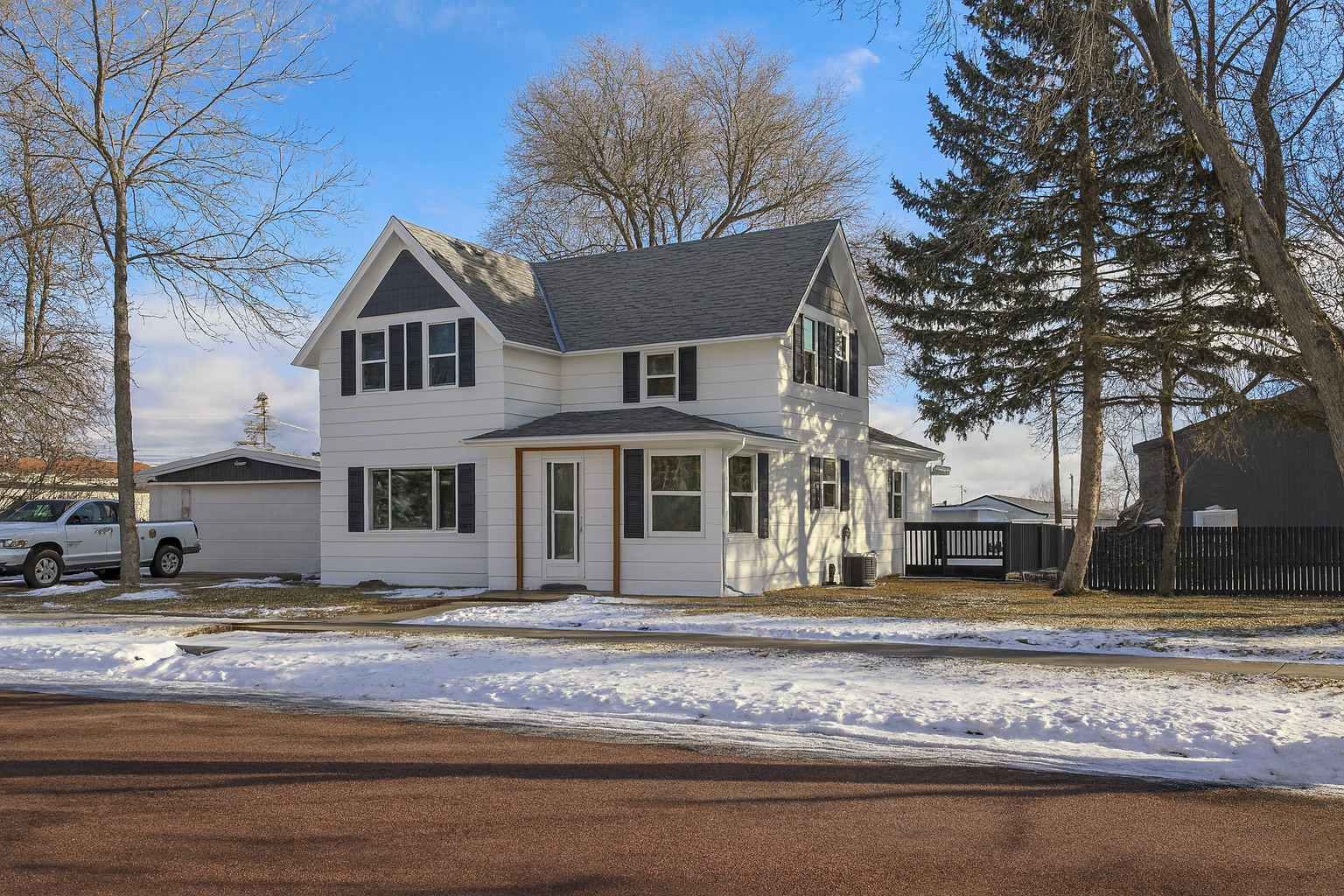 Cozy Cape Cod Home Surrounded by Greenery in Sioux Falls A quaint Cape Cod-style home with beige siding and white window frames, nestled among mature trees in a lush green lawn, located at 2201 S Euclid Ave, Sioux Falls, SD.
